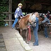 Junge Reiterin beim Aufstieg auf ein Pferd von der behindertengerechten Reiterrampe